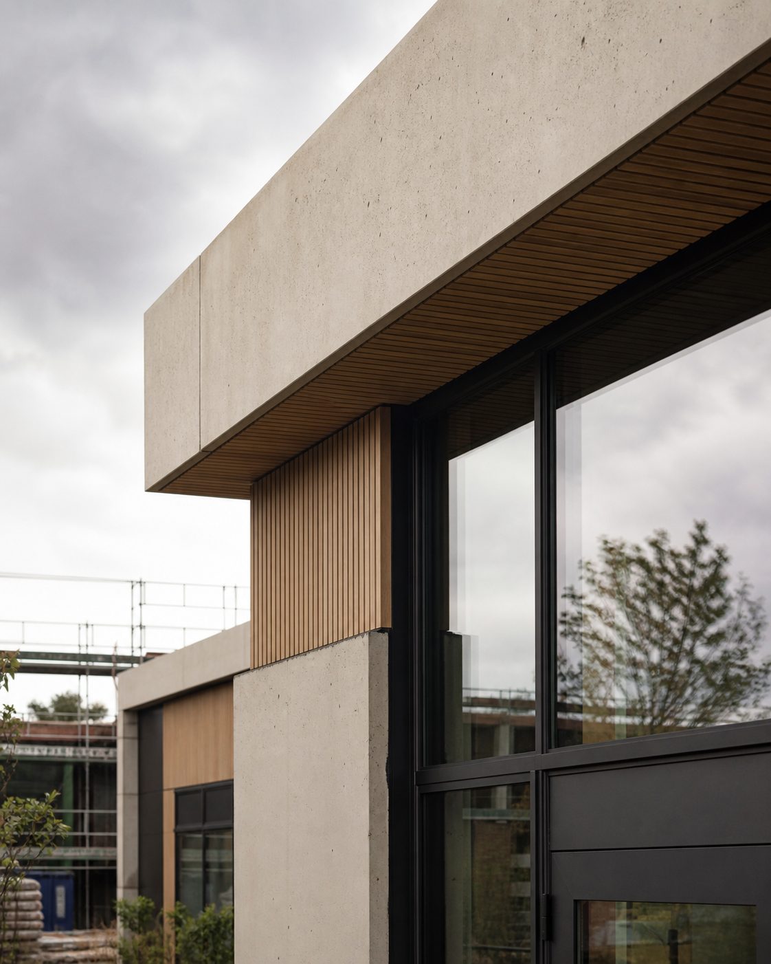 Facade med beton, trælameller og mørke vinduesrammer
